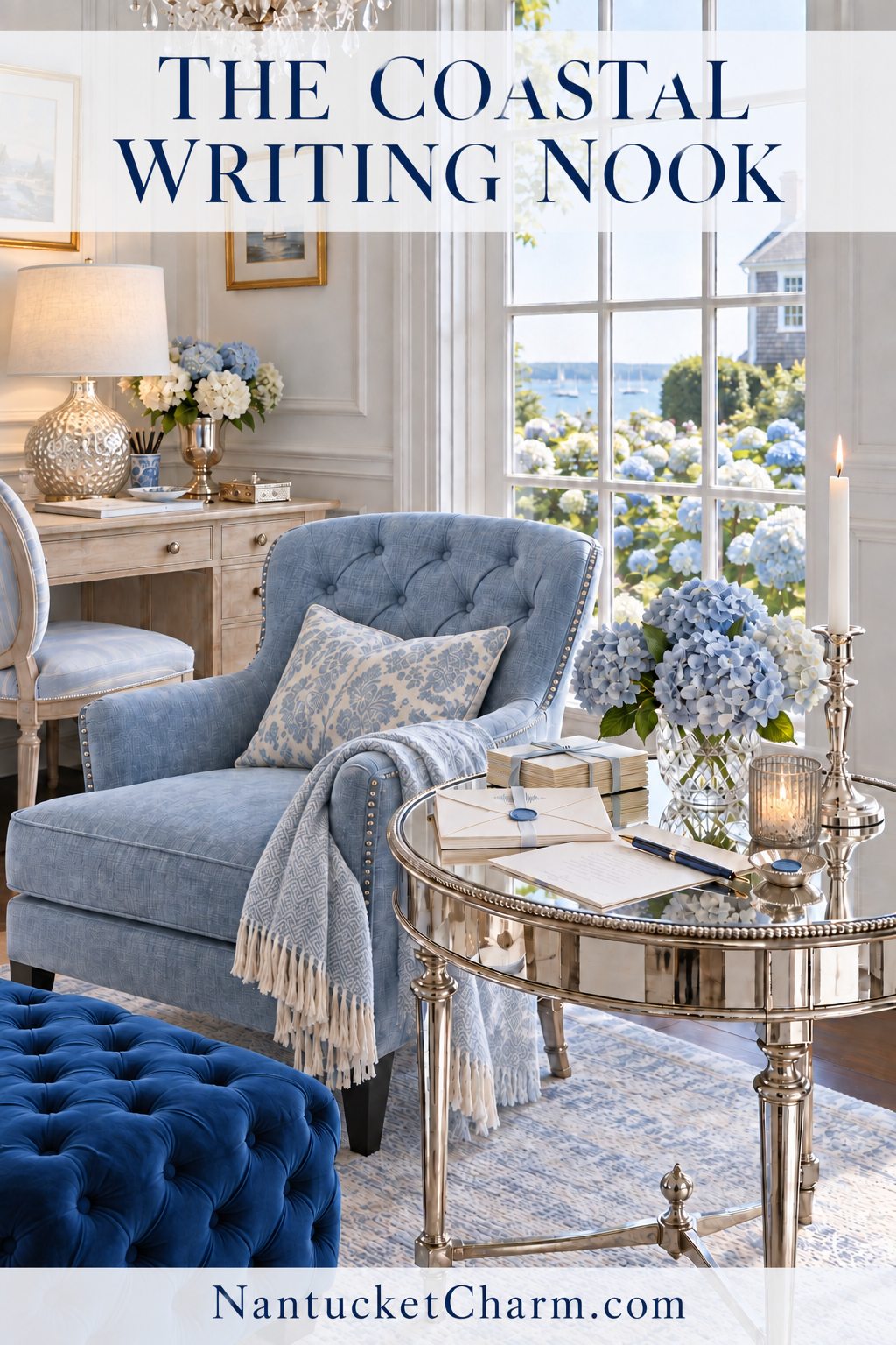Coastal writing nook with a light blue tufted nailhead chair, blue damask pillow, fringed blue throw, round mirrored side table with letters and a fountain pen, silver candlestick, blue hydrangeas in a blue-and-white vase, aged white writing desk with a mercury glass lamp, navy velvet ottoman and a faded blue rug by a harbor-view window.