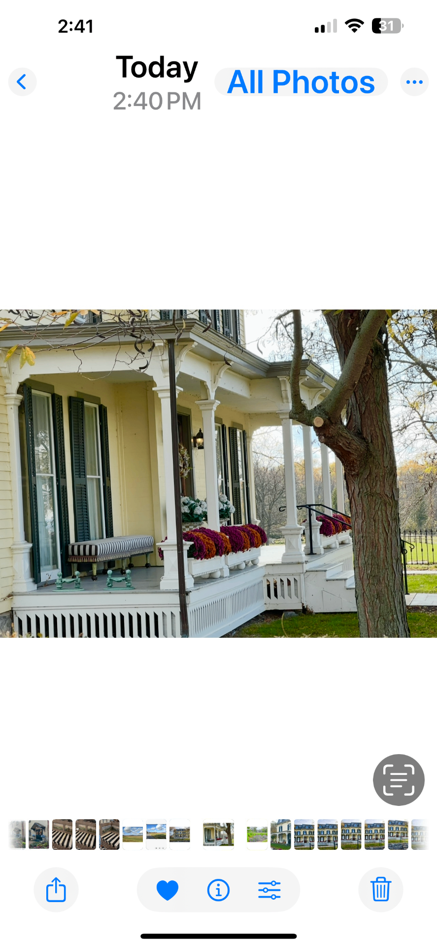 The Farmhouse front porch in autumn with striped bench and window boxes of burgundy and gold mums