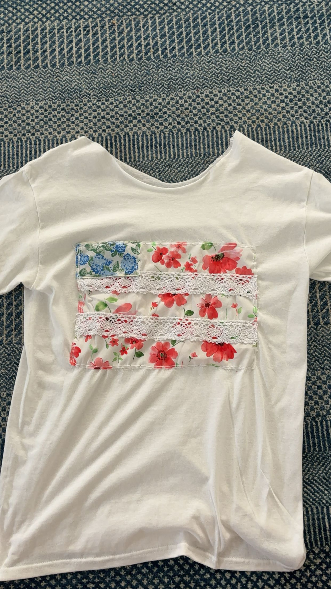 Close-up of the handmade appliqué flag on the white cotton tee showing lace stripes and red star detail