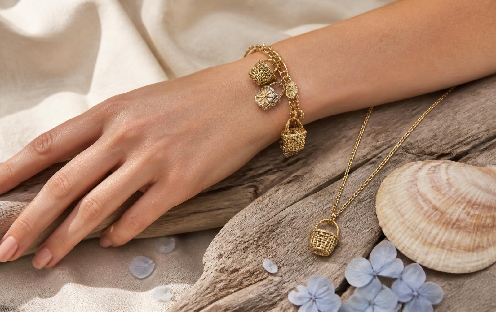 A 14k gold Nantucket lightship basket charm bracelet and basket pendant necklace on driftwood with blue hydrangea petals